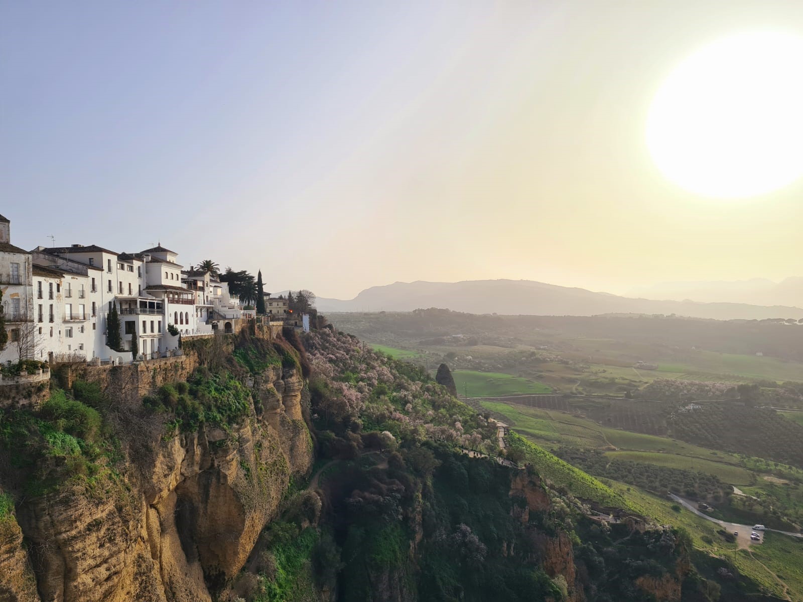 Eine sonnige Klippenlandschaft in Spanien mit kleinen hellen Häusern und einem weitläufigen Tal im Hintergrund.