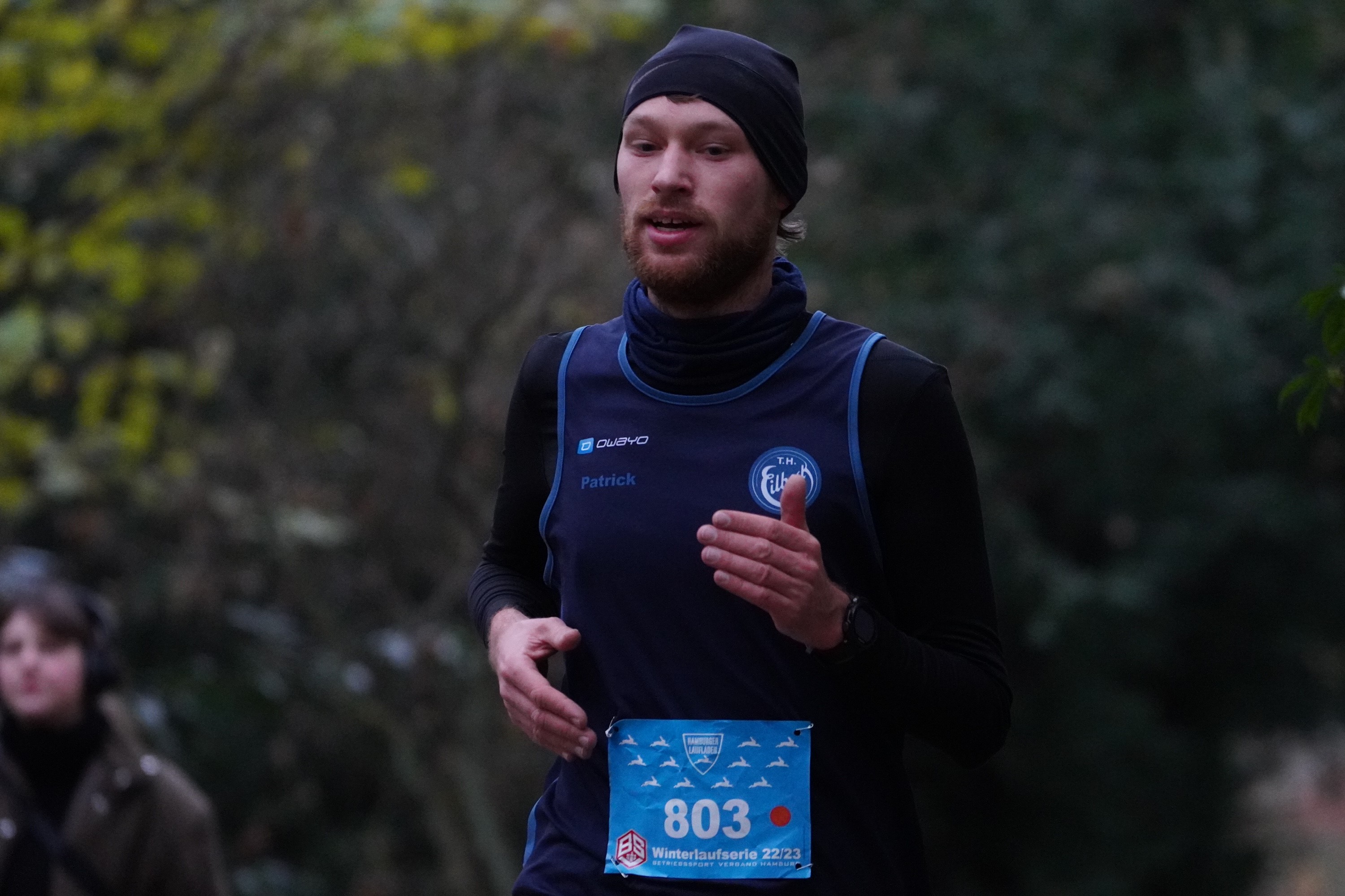 Ein junger Mann (Florian Thieben) mit Vollbart und einer dunkelblauen Mütze im Lauf. Im Hintergrund ist verschwommen Wald zu erkennen.